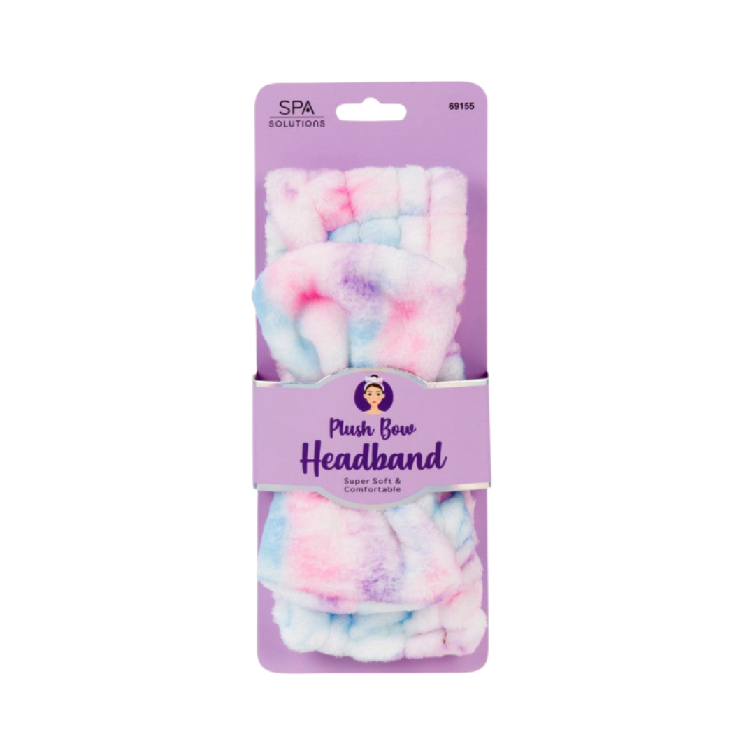 Spa Solutions plush bow headband in pink, blue, and purple tie-dye fabric on purple card packaging.