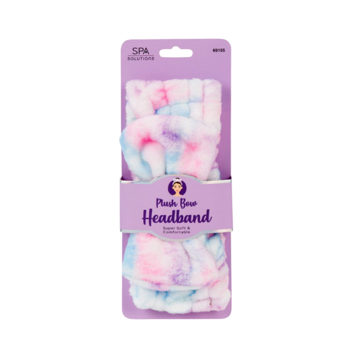 Spa Solutions plush bow headband in pink, blue, and purple tie-dye fabric on purple card packaging.
