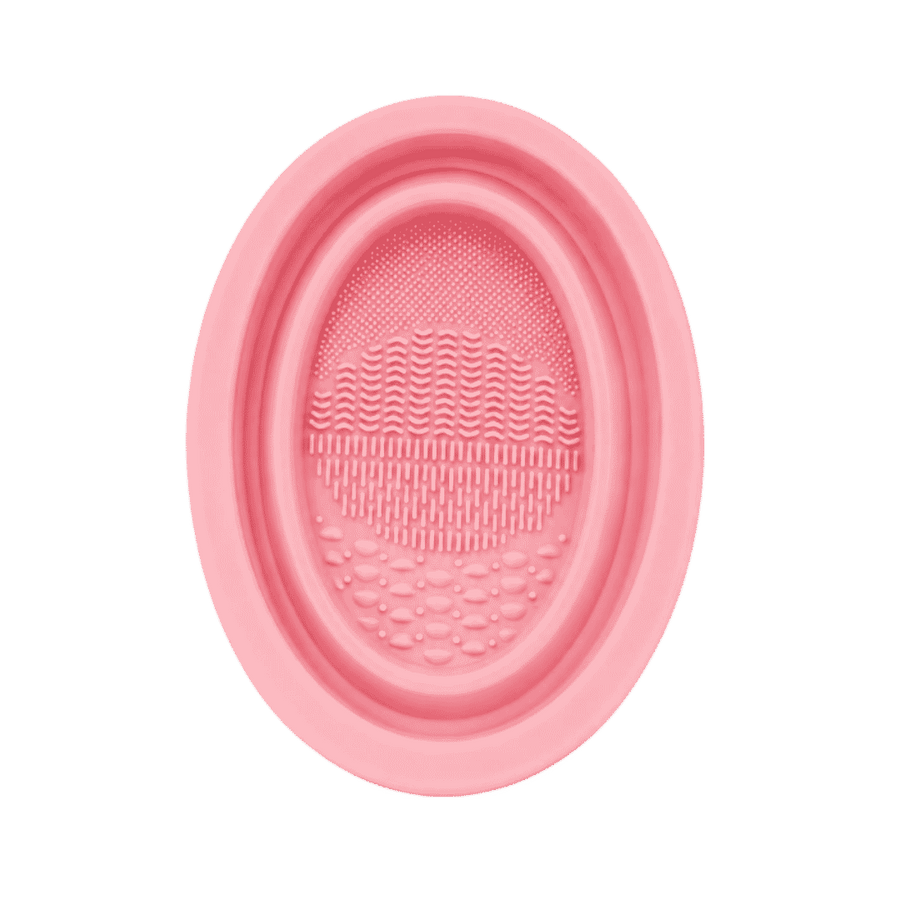 KOHR pink silicone makeup brush cleaning pad with oval shape and multiple textured washing surfaces.