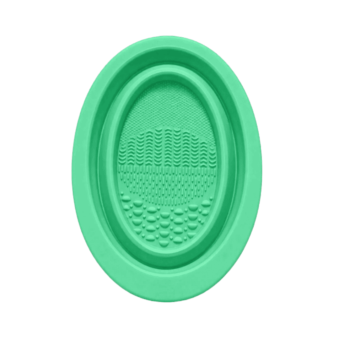 Green oval silicone facial cleansing brush with textured surface and raised cleansing bristles.
