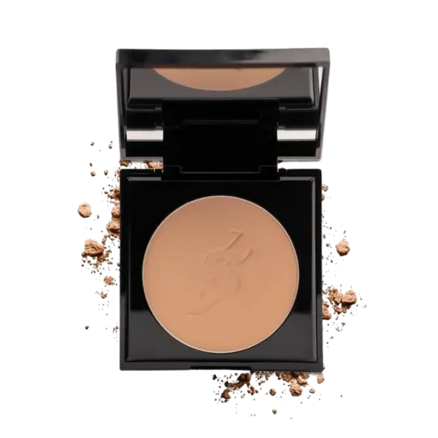 Open black compact with mirror, beige pressed face powder pan, scattered powder crumbs.
