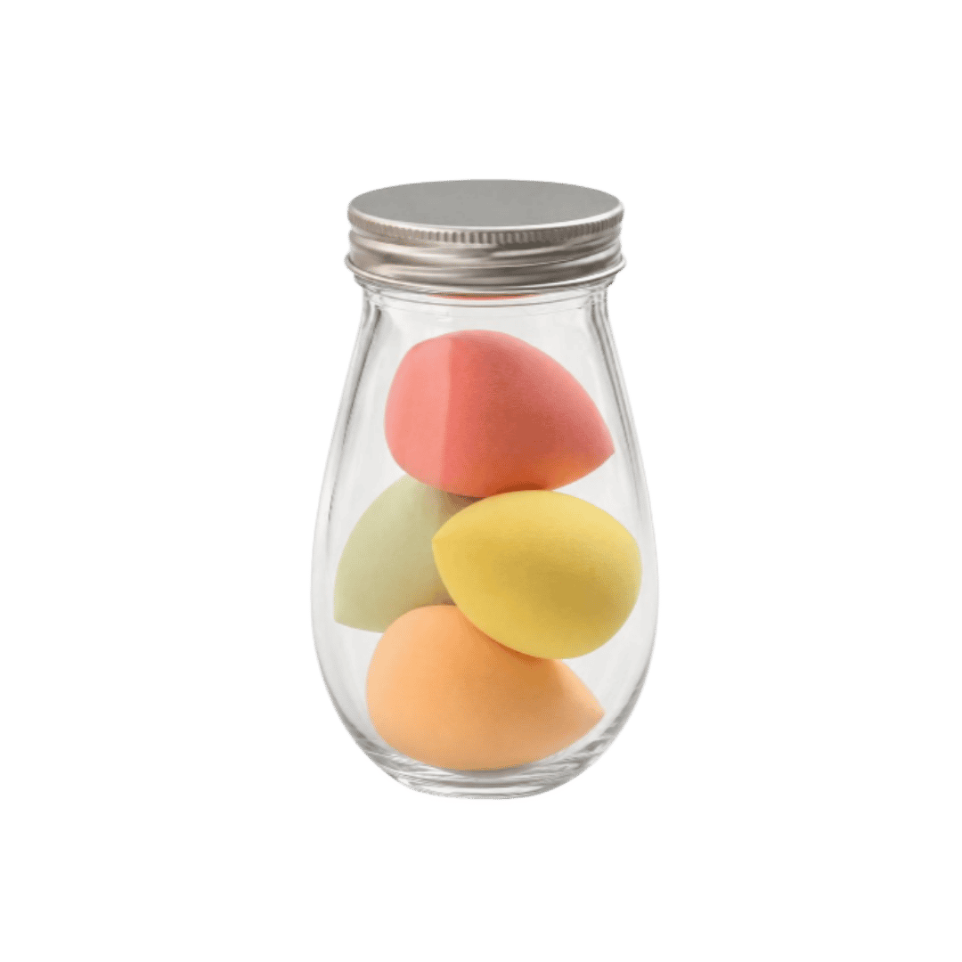 Four teardrop makeup sponges in clear glass jar with silver lid, peach, yellow, green, and pink.