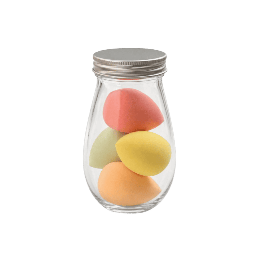 Four teardrop makeup sponges in clear glass jar with silver lid, peach, yellow, green, and pink.
