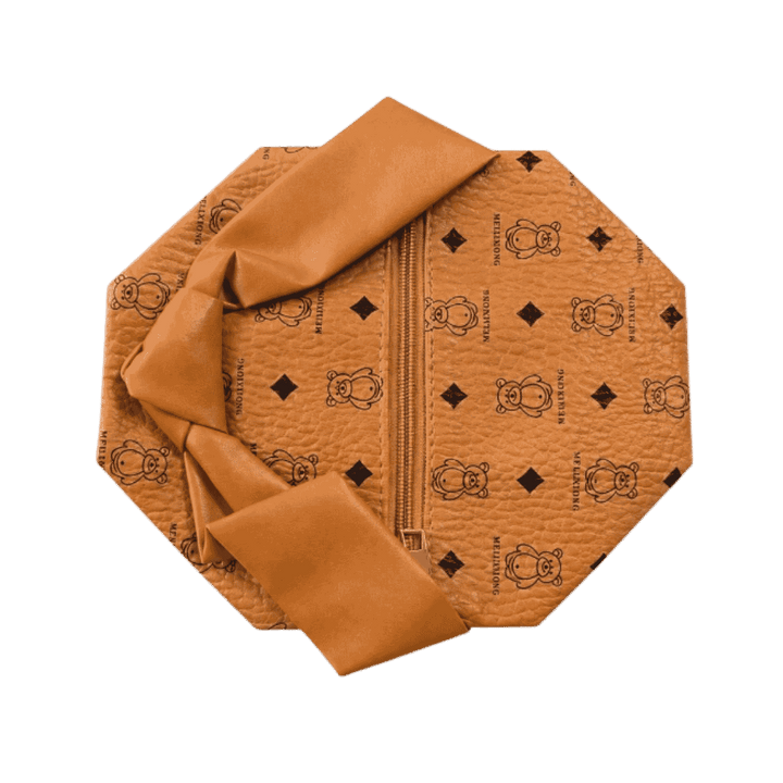 Brown leather washbag with zip closure, black printed motifs, and wide matching decorative strap.